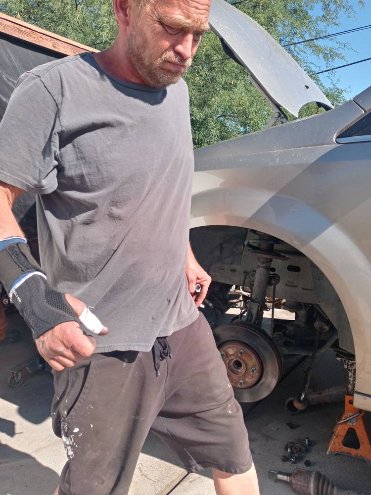Robert Kious doing a brake job, wheel off and car on a jack stand